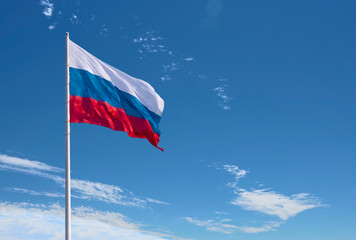 Waving Russian flag against a blue sky with clouds and empty space for text. Room for text.