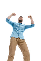 low angle surprising enthusiastic young guy with arms in the air