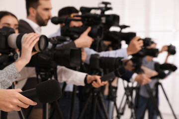 Group of journalists with cameras waiting for official person indoors, closeup