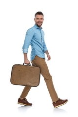 sexy young man in denim shirt holding luggage, enjoying days off