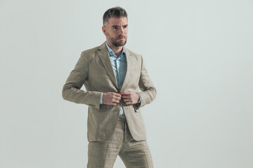 attractive young man looking away and unbuttoning suit