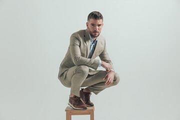 attractive man in his forties holding elbows on knees and crouching