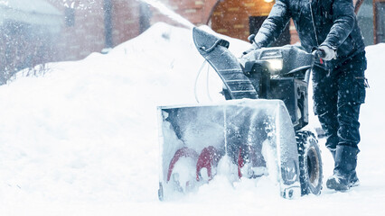 a janitor on a snowplow removes snow in the courtyard of a residential building
