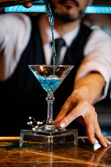 Barman is making cocktail at night club.