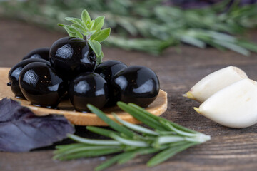 olives with spices and rosemary in a wooden spoon