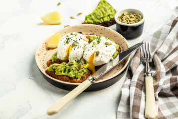 Avocado Sandwich with Poached Egg on toasted bread on a light background. banner, menu recipe place for text, top view