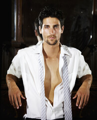 Just you and me. A handsome young man leaning on a bar counter with his shirt slightly open.