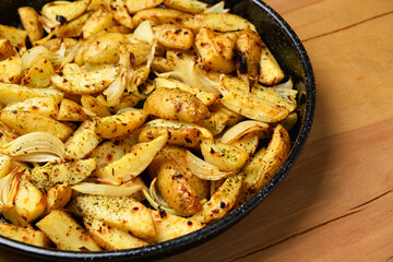 roasted potatoes in a frying pan, cooked food, delicious crust, one object on a wooden background