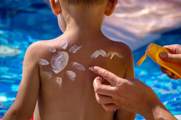 Mother puts cream on her son's back. Caring for baby skin. Sunscreens in the travel. selective focus