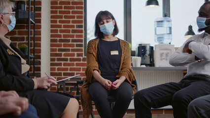 Sad woman crying at aa therapy meeting in front of group of people during covid 19 pandemic....