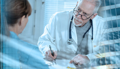 Obraz na płótnie Canvas Senior doctor writing prescription to his patient; light effect; multiple exposure