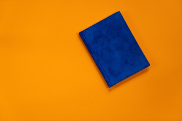 Navy blue notepad with white sheets on summer orange background. Plans for summer to do list