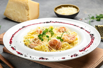Pasta with grilled shrimps, bechamel sauce, cheese and microgreen, italian cuisine, Food recipe background. Close up
