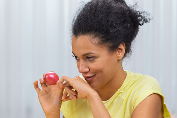 Cute African American woman talking by video call on a laptop. A young woman demonstrates a Easter painted egg while sitting at a decorated holiday table. Happy easter. Close up.