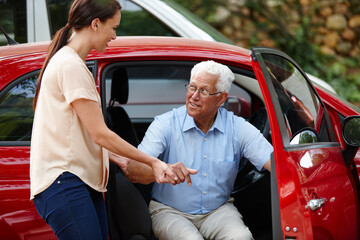 Let me help you out of the car. Shot of a woman helping her senior father out of the car.