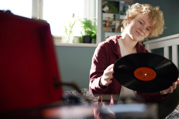 Teenage Girl Playing Vinyl Records On Record Player At Home In Bedroom