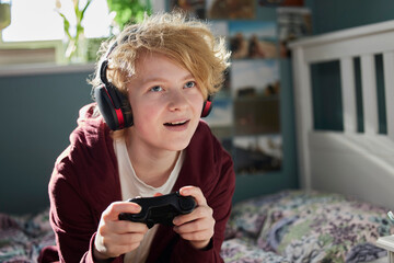 Excited Teeange Girl With Wireless Headphones Gaming Online In Bedroom At Home