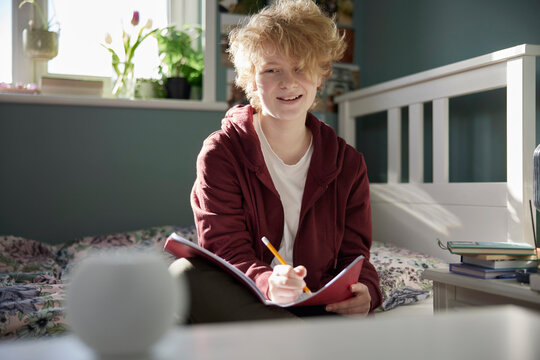 Teenage Girl Doing Homework At Home Asking Digital Assistant Question