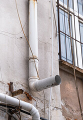 plastic rain gutter on old and dirty building wall