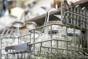 Open dishwasher with clean glass and dishes, selective focus