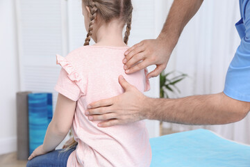 Orthopedist examining child's back in clinic, closeup. Scoliosis treatment