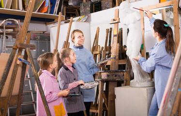 Young woman says her female students painting techniques in a workshop on painting