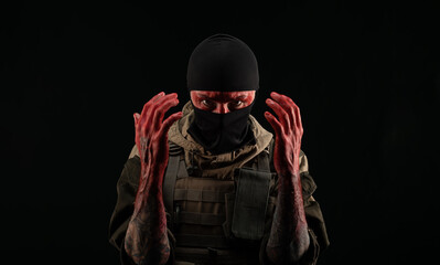 photo of a man in a military uniform and balaclava with a bloody face and hands up to the elbow in blood on a black background