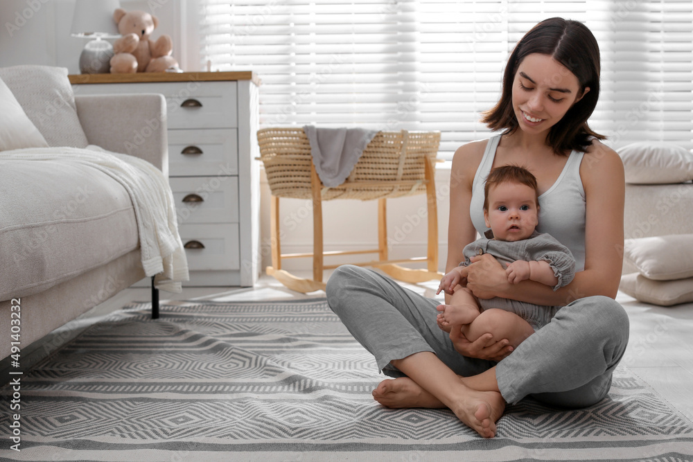 Poster Young woman with her little baby on floor at home