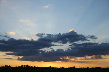 The summer sunset, sun rays shining through dark rain clouds.
