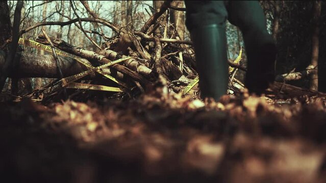 Man walks into a crime scene in the woods. Taped and cornered off area with Crime Scene Tape all around the crime site. Killer on the lose