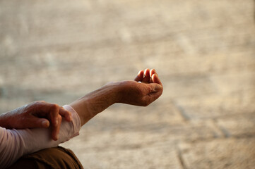 Hands of a person in financial need extended to request donations from passersby on a street in Jerusalem.