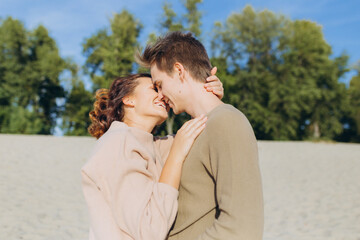 Fototapeta premium portrait of a couple in love. Happy romantic young couple enjoying the sunset. The guy hugs the girl and kisses her on the lips