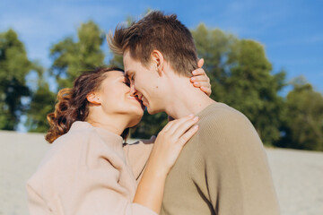 portrait of a couple in love. Happy romantic young couple enjoying the sunset. The guy hugs the girl and kisses her on the lips