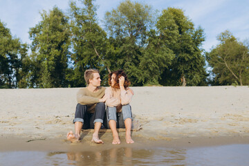 A loving couple has fun - they laugh, hug each other and enjoy a warm summer evening. Romantic couple sitting by the sea. The guy and the girl look at each other