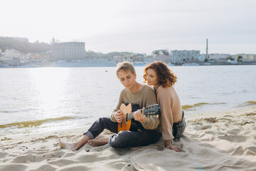 Fototapeta na wymiar Man flirting playing guitar while a girl looks him amazed with the sea in the background