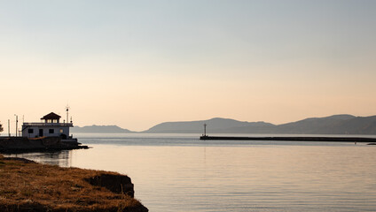 Coastline, fishing house and pier with fishermen in calm Mediterranean Sea, Greece