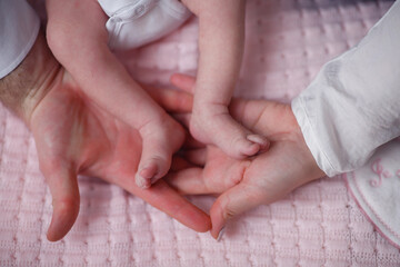 The hands of the mother and father are holding the little feet of the child in the palms, close-up...