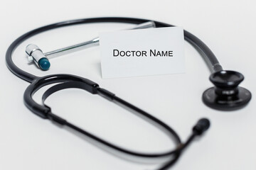 blank doctor business card on white background near medical instruments, black fenendoscope, reflex hammer