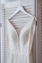 Classic wedding long white sleeveless dress on a hanger hanging on a wooden screen