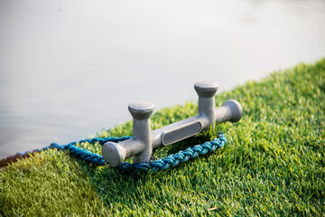 Fototapeta premium Double cross bollard or bitteng with a tied rope on the dock. towing mooring gear