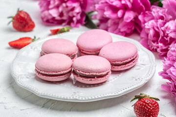 Obraz na płótnie Canvas pink macaron or macaroon cakes with peony rose on a white background. Banner, flyer, beautiful postcard, top view
