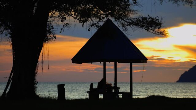 Unidentifed people on small hut enjoying beautiful sunset at Tanjung aru beach, Kota Kinabalu, Sabah, Malaysia