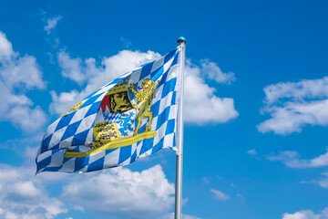 View of a Bavarian flag waving in the wind in front of a white-blue sky 