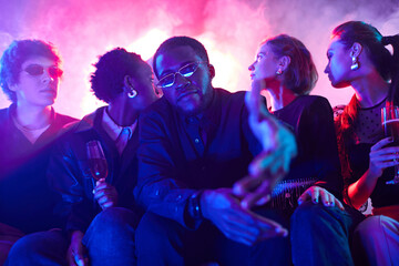 Portrait of young African American man with diverse group of friends at party in neon lights