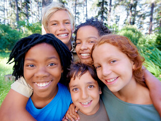 Fun, friends and fresh air. A closeup of image of a group of kids smiling at the camera while standing in the woods.