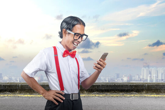 Asian nerd with an ugly face holding mobile phone