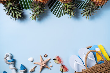 Summer fruit background design concept. Beach with shells, hat, pineapple and palm leaves on blue background.