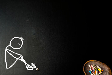 Lonely and sad stickman sitting on the floor, blackboard backgound.