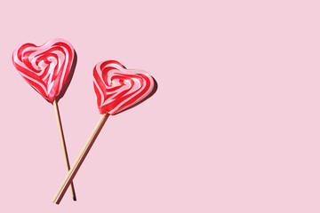 two heart-shaped lollipops on a pink background, copy space for text, Red and whie striped sweet...