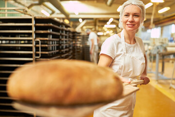 Junge Frau als Bäckerin mit Brot Laib auf einem Brotschieber